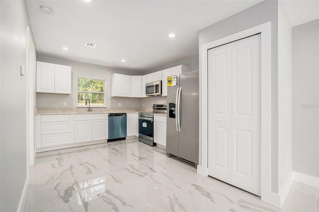 kitchen featuring marble finish floor, a sink, stainless steel appliances, white cabinets, and light countertops