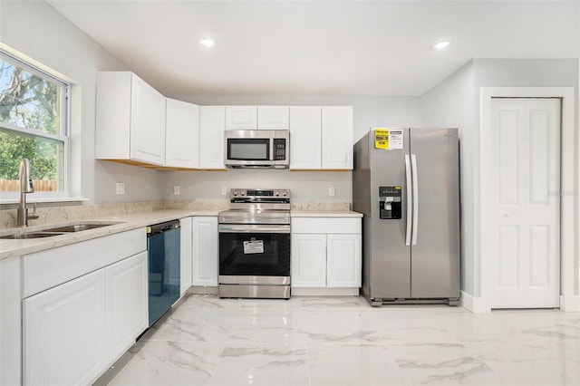 kitchen featuring recessed lighting, stainless steel appliances, marble finish floor, white cabinetry, and a sink