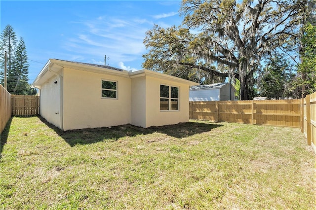 back of property featuring a yard, a fenced backyard, and stucco siding