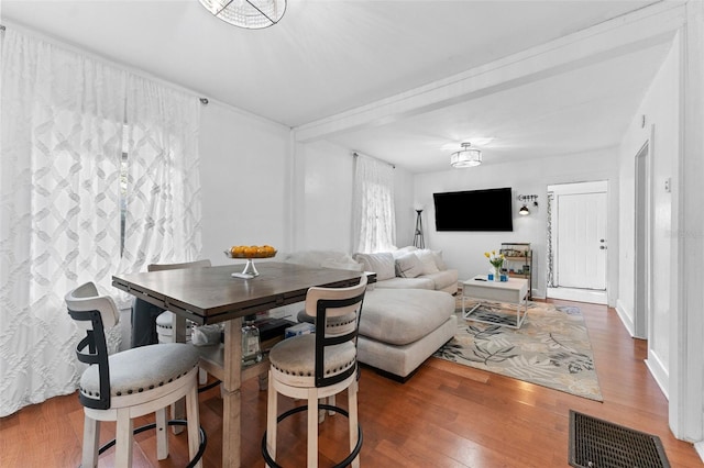 dining space with wood finished floors, visible vents, and baseboards