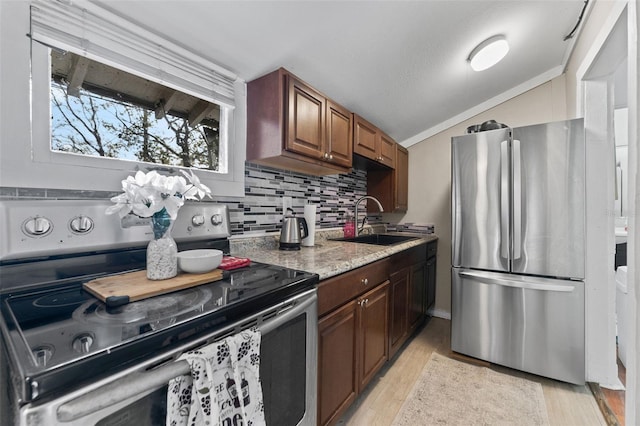 kitchen with a sink, tasteful backsplash, stainless steel appliances, light wood-style floors, and vaulted ceiling