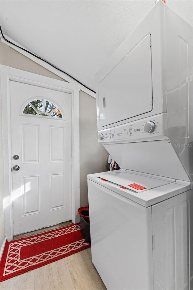 laundry area featuring laundry area, light wood-type flooring, and stacked washer / drying machine