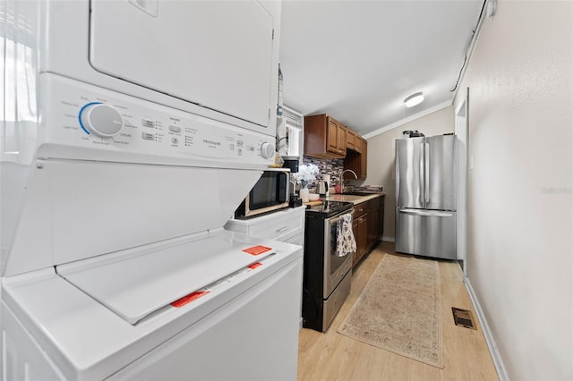 kitchen with stainless steel appliances, visible vents, light wood-style flooring, and stacked washer / drying machine