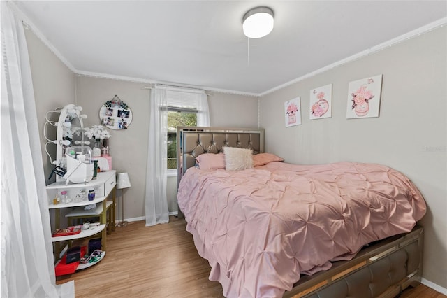 bedroom featuring crown molding, baseboards, and wood finished floors