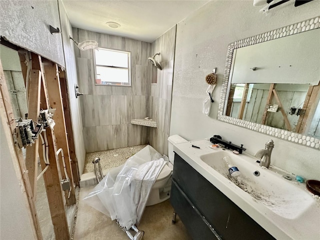 full bath featuring vanity, a tub to relax in, walk in shower, toilet, and a textured wall