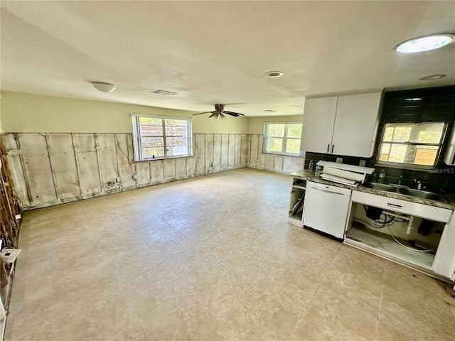 kitchen featuring visible vents, dishwasher, a wealth of natural light, wainscoting, and a sink