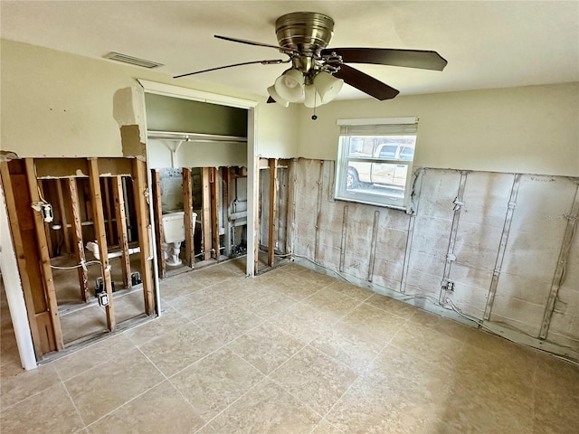 spare room with ceiling fan, visible vents, and a wainscoted wall