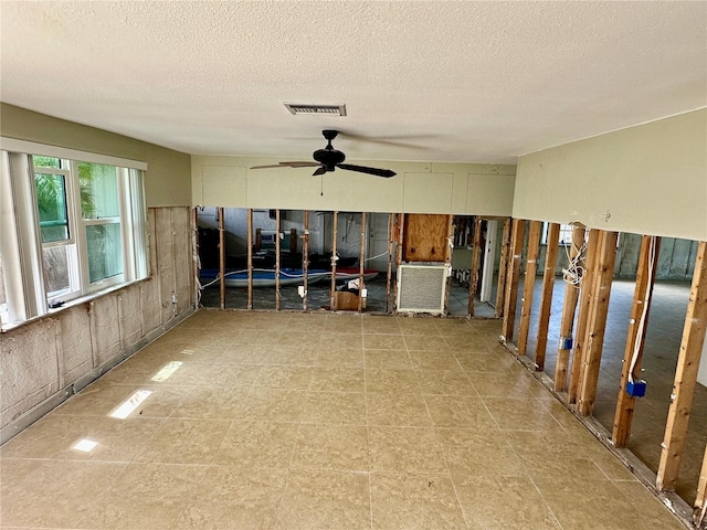 interior space with a ceiling fan, visible vents, and a textured ceiling