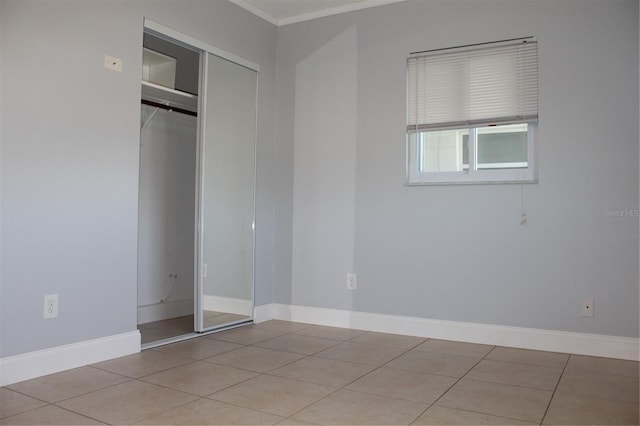 unfurnished bedroom with tile patterned flooring, a closet, and baseboards