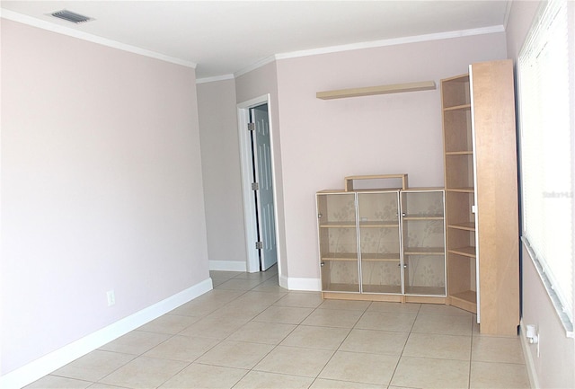 empty room with tile patterned floors, visible vents, ornamental molding, baseboards, and a healthy amount of sunlight