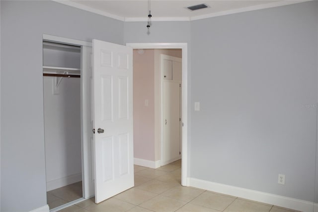 unfurnished bedroom featuring visible vents, baseboards, ornamental molding, light tile patterned floors, and a closet