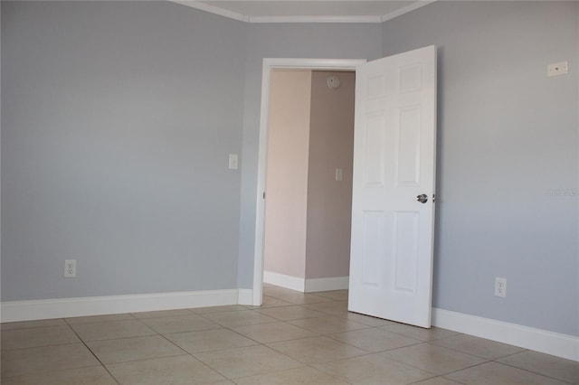 spare room with baseboards, ornamental molding, and light tile patterned flooring