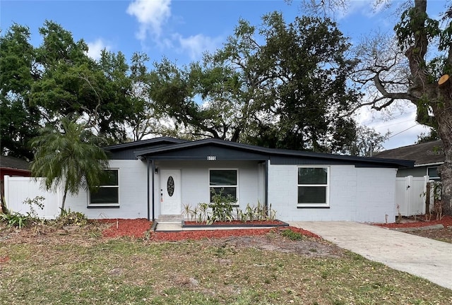 ranch-style house with concrete block siding and fence