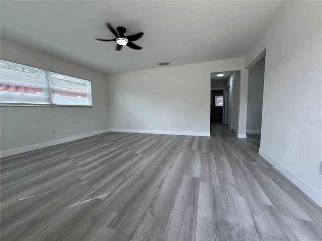 empty room with visible vents, baseboards, wood finished floors, and a ceiling fan