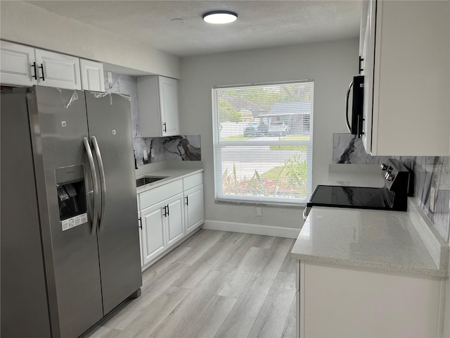 kitchen featuring light wood-type flooring, backsplash, white cabinetry, stainless steel appliances, and baseboards