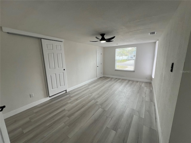 unfurnished bedroom featuring visible vents, light wood-type flooring, and baseboards