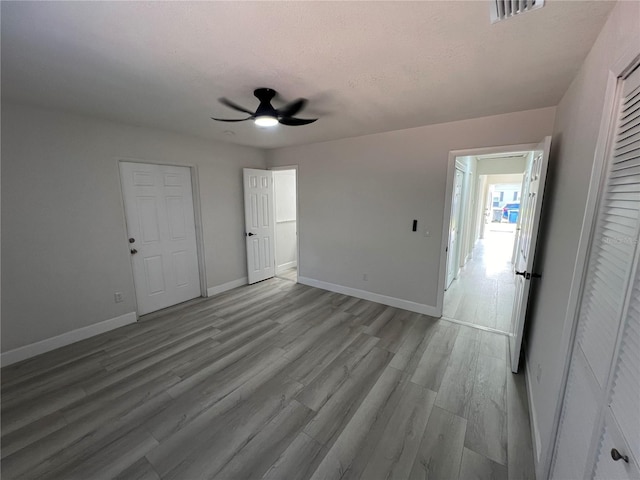 unfurnished bedroom with baseboards, visible vents, ceiling fan, a textured ceiling, and light wood-type flooring