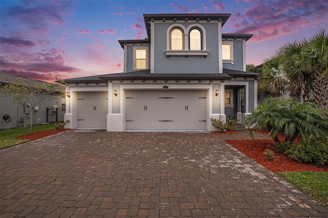 view of front of home with stucco siding, an attached garage, decorative driveway, and fence