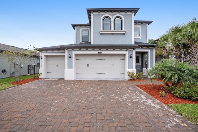 view of front of property with stucco siding, decorative driveway, and a garage