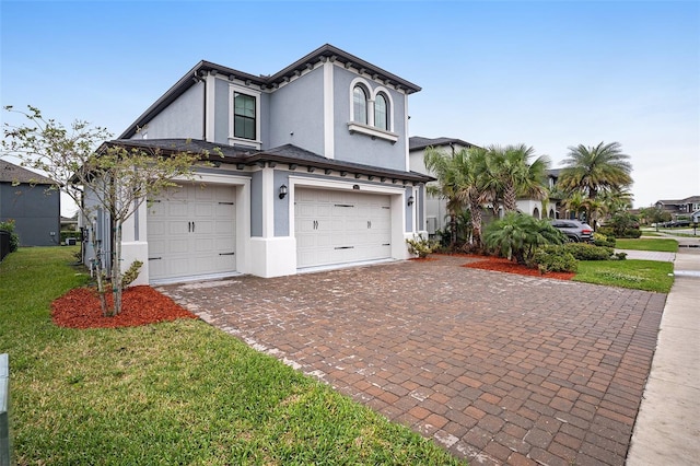 view of front of home with stucco siding, decorative driveway, a garage, and a front lawn