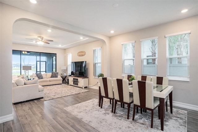 dining space featuring recessed lighting, wood finished floors, baseboards, and arched walkways