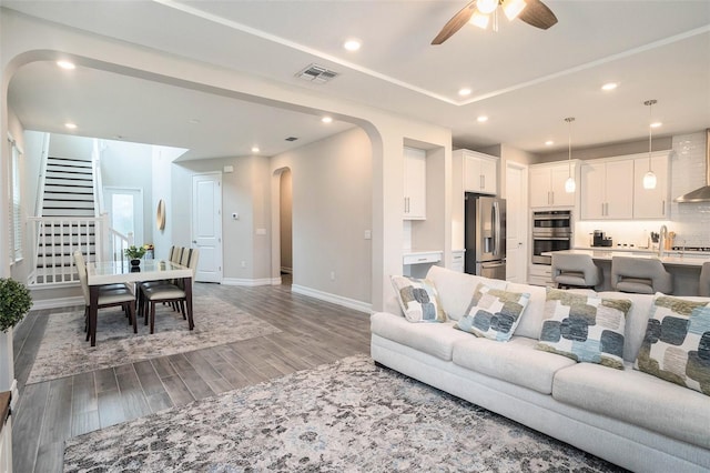 living area featuring stairs, recessed lighting, light wood-style floors, arched walkways, and a ceiling fan