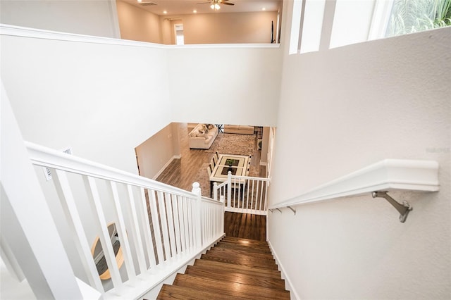 staircase with visible vents, a high ceiling, wood finished floors, and a ceiling fan