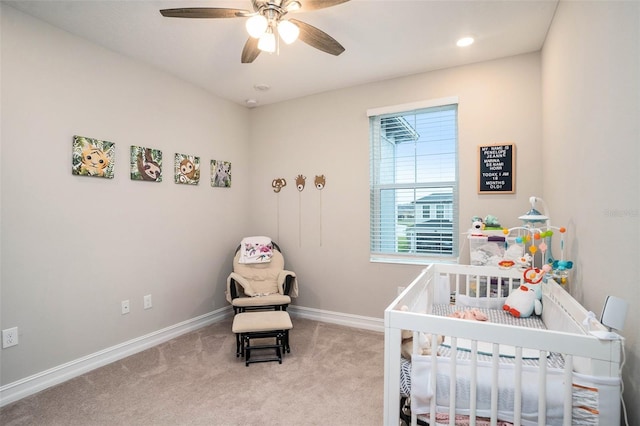 bedroom featuring baseboards, a ceiling fan, a nursery area, and carpet floors