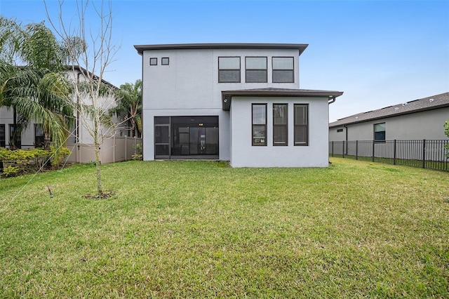 back of property with stucco siding, a lawn, a sunroom, and fence