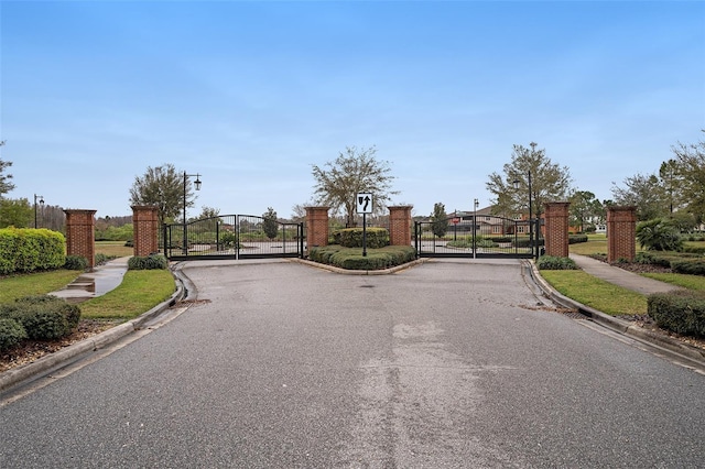 view of street with sidewalks, curbs, and a gate