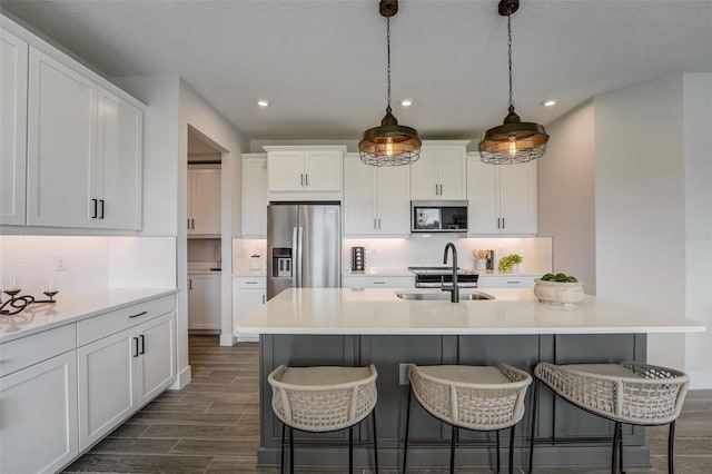 kitchen featuring a sink, backsplash, stainless steel appliances, a breakfast bar area, and wood tiled floor