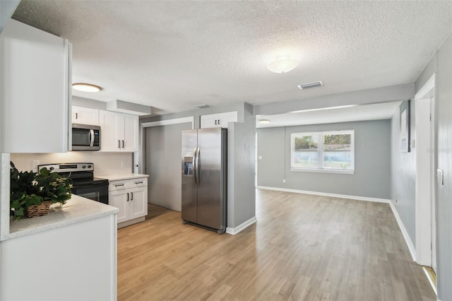 kitchen with light wood-type flooring, stainless steel appliances, visible vents, and white cabinetry