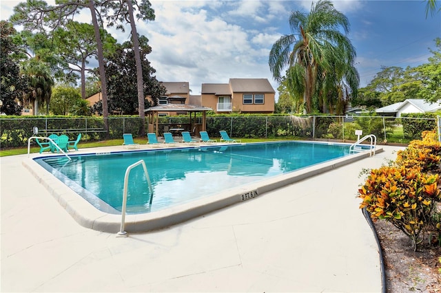 community pool with a gazebo, a patio, and fence