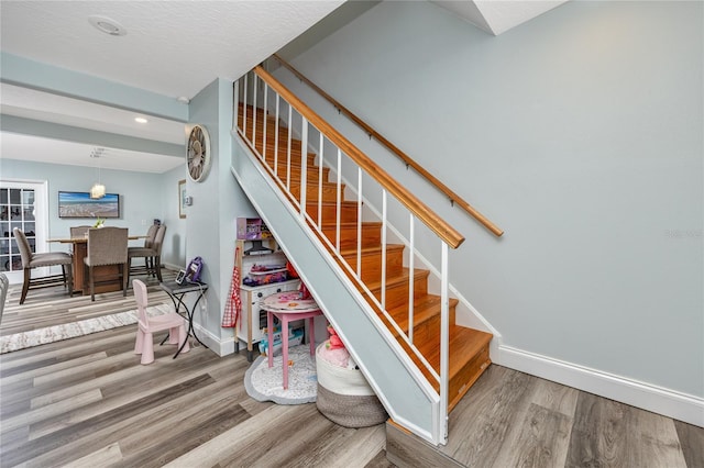 stairway with recessed lighting, wood finished floors, and baseboards