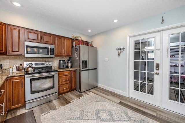 kitchen featuring backsplash, french doors, stainless steel appliances, and light wood-type flooring