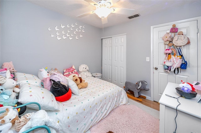 bedroom with light wood-type flooring, visible vents, a closet, and ceiling fan