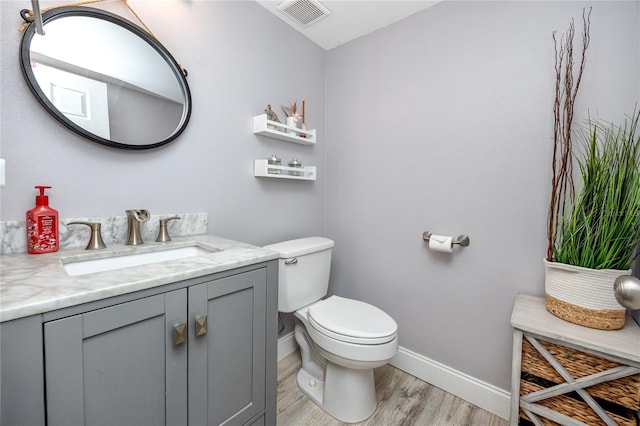 bathroom with vanity, wood finished floors, visible vents, baseboards, and toilet