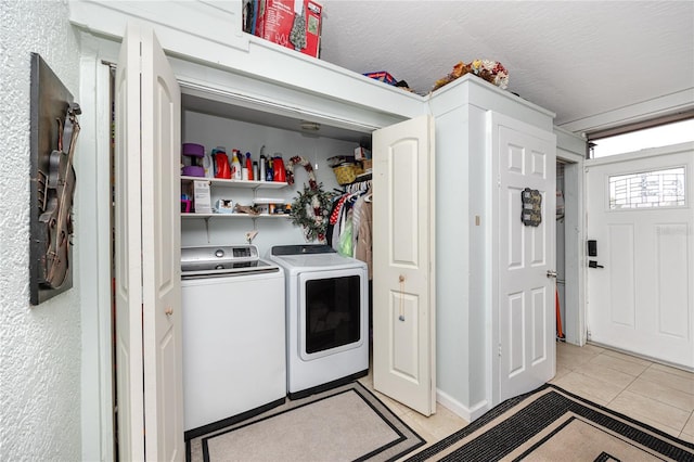 clothes washing area with washer and clothes dryer, laundry area, a textured ceiling, and light tile patterned floors