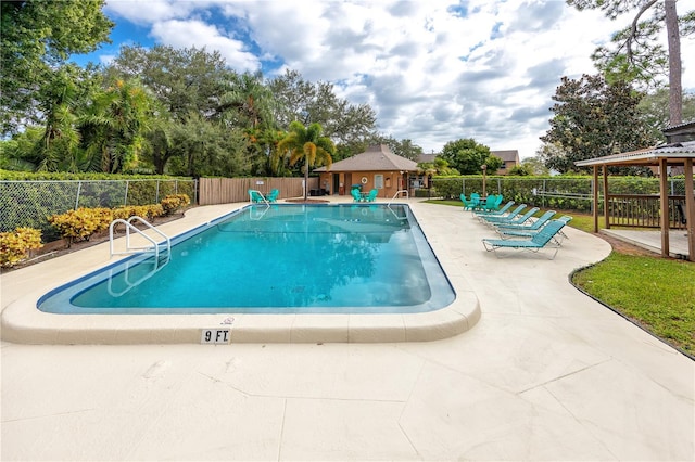 community pool featuring an outbuilding, a patio, and fence