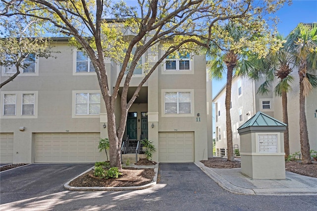 multi unit property featuring aphalt driveway, stucco siding, and an attached garage