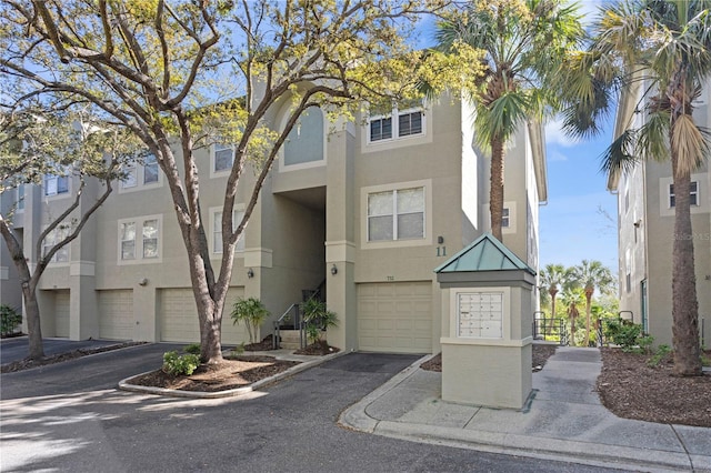 townhome / multi-family property featuring aphalt driveway, an attached garage, and stucco siding