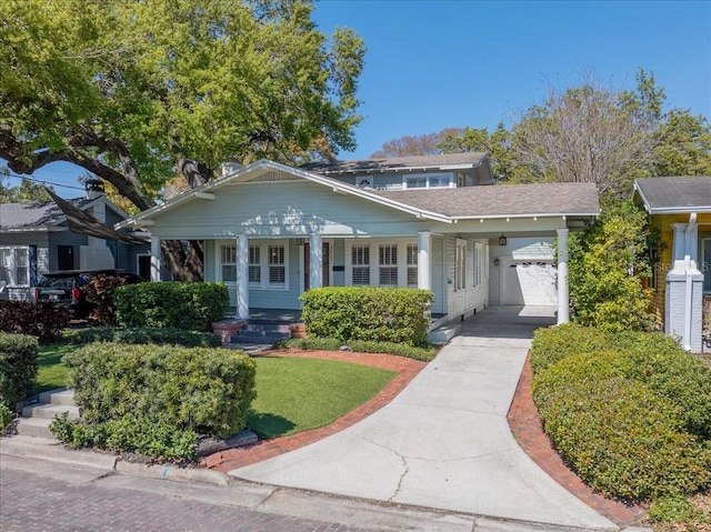 view of front facade featuring a front yard, an attached carport, covered porch, and driveway