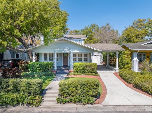 bungalow-style home with an attached carport, a porch, and concrete driveway