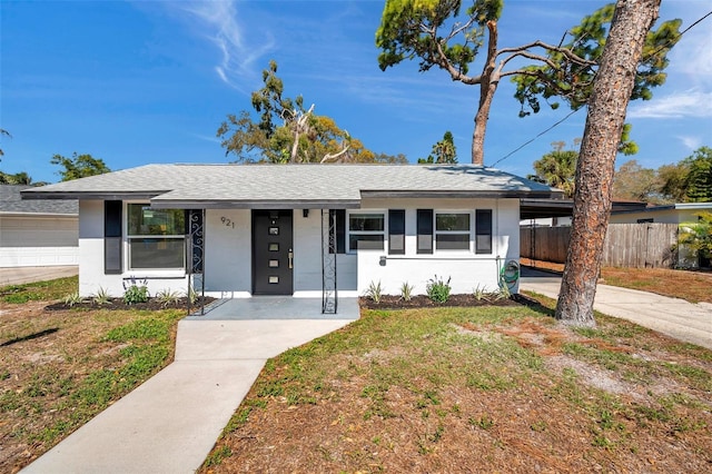 single story home featuring a front lawn, fence, roof with shingles, and stucco siding