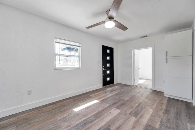 spare room featuring visible vents, wood finished floors, baseboards, and ceiling fan