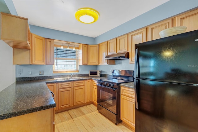 kitchen featuring dark countertops, under cabinet range hood, light wood-style flooring, black appliances, and a sink