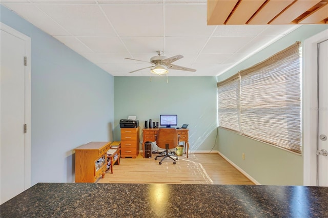 home office featuring a ceiling fan, wood finished floors, a paneled ceiling, and baseboards