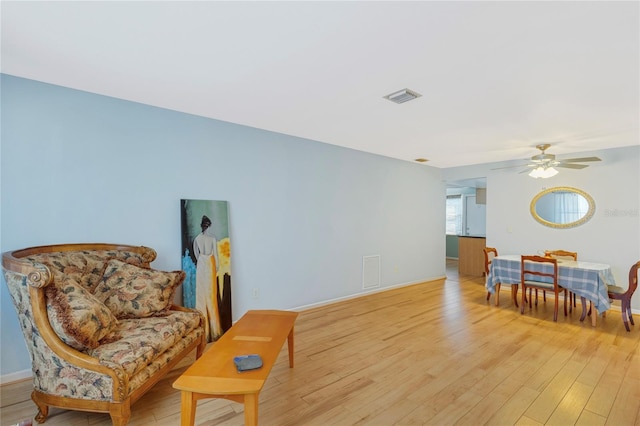 sitting room featuring visible vents, baseboards, ceiling fan, and light wood finished floors