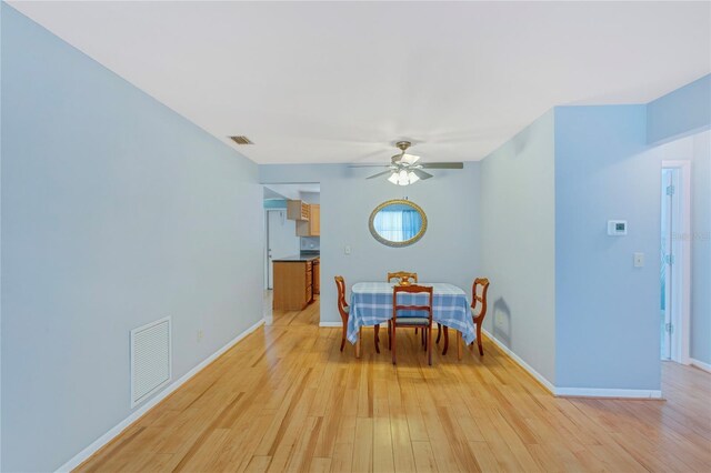 dining room with light wood-style flooring, baseboards, visible vents, and ceiling fan