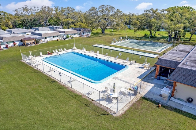 community pool with a yard, a patio, and fence